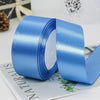 A roll of light blue satin ribbon is shown unwound, lying on a piece of paper.