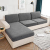 A light beige waterproof jacquard stretch sofa cover displayed on a modern sofa in a bright living room.