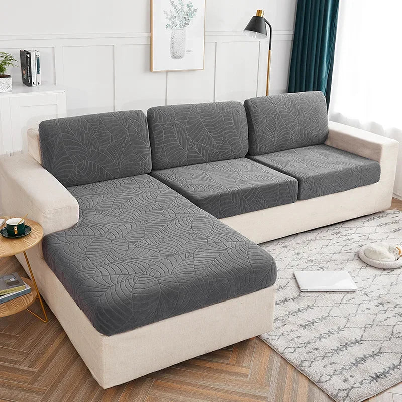A light beige waterproof jacquard stretch sofa cover displayed on a modern sofa in a bright living room.
