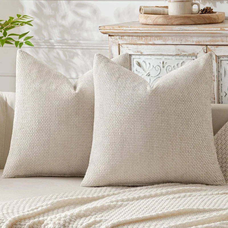 A pair of beige breathable chenille pillows with a textured weave resting on a light-colored sofa.