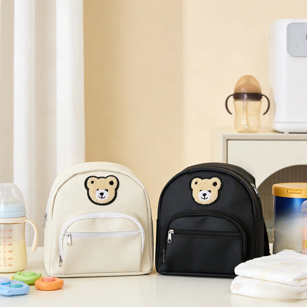 A beige and black embroidered bear stroller organizer bag resting on a white surface.