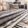 Gray and beige plush velvet sofa protector covers draped over a white sofa with decorative pillows.