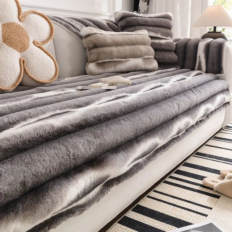 Gray and beige plush velvet sofa protector covers draped over a white sofa with decorative pillows.