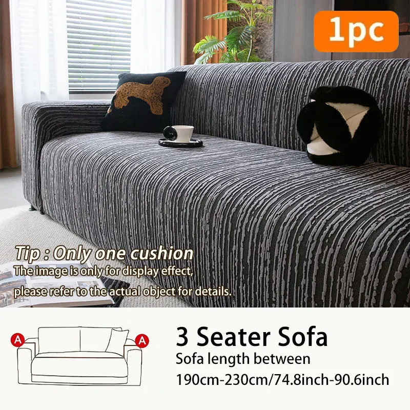 A dark gray jacquard plush elastic sofa cover with a black cushion displayed on a sofa.