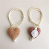 Pair of handmade plush heart tiebacks made of cream and pink fuzzy fabric with pearl accents