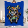A blue flannel throw blanket featuring a graphic of Monster Jam vehicles and a woman's face.