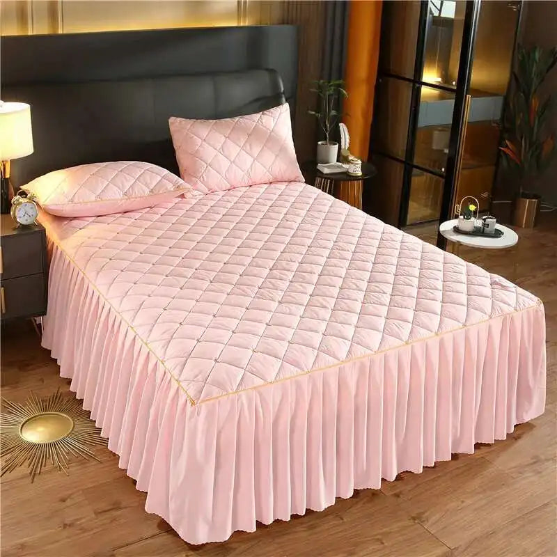 Pink quilted bed skirt with a diamond pattern covering a queen mattress.