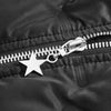 Close-up of a black quilted fabric with a silver metal zipper pull featuring a star charm.