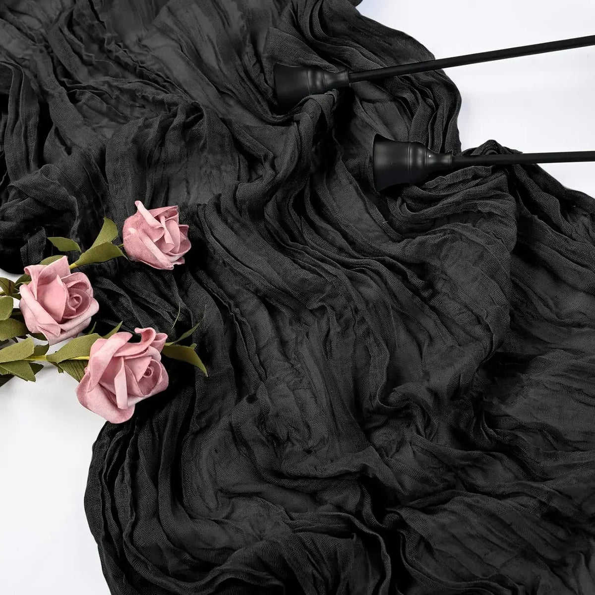 Black rustic gauze fabric draped with dark pink roses and black paintbrushes