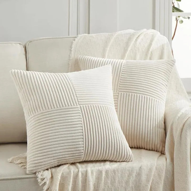 A close-up of a cream colored patchwork pillow cover with vertical ribbed texture resting on a light beige sofa.
