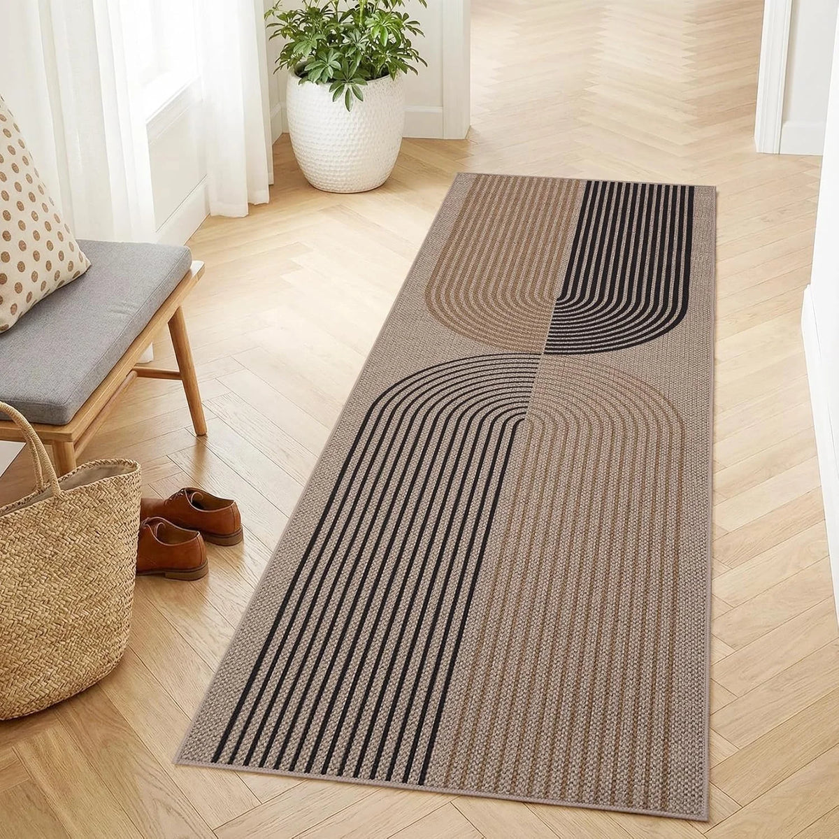 A long runner rug with geometric stripes in beige and black tones placed on a light wood floor.