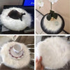 A round white faux fur sheepskin rug with a dark brown object and a small teacup placed on it.
