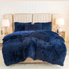 A dark blue plush duvet cover set displayed on a bed with upholstered headboards and bedside lamps.