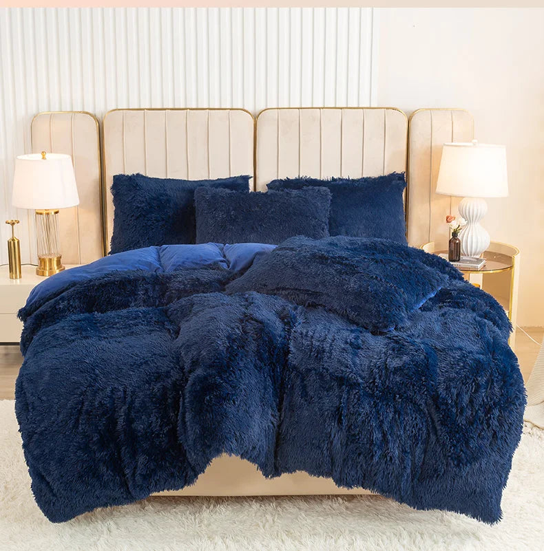 A dark blue plush duvet cover set displayed on a bed with upholstered headboards and bedside lamps.