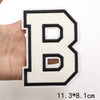 A hand holds a white letter B patch with black outline and embroidery on a white background.