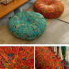 A vibrant orange and teal bohemian cotton linen throw cushion resting on a wooden table.