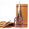 Vintage stainless steel sewing scissors with decorative handles resting on a wooden surface.