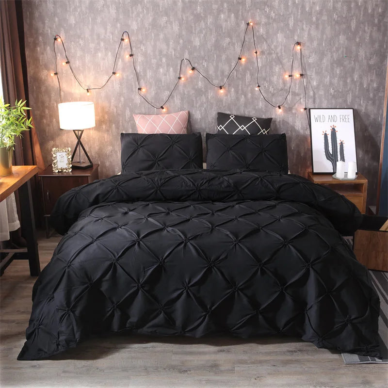 A black quilted duvet and pillows displayed on a bed with string lights in a bedroom setting.