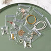Clear plastic self-sealing jewelry storage bags filled with various gold and silver rings, necklaces, and earrings arranged o