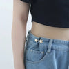 A close-up of a denim jean pocket featuring a gold star brooch pin.