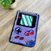 A purple tufted floor mat shaped like a retro video game controller with green and white graphics.