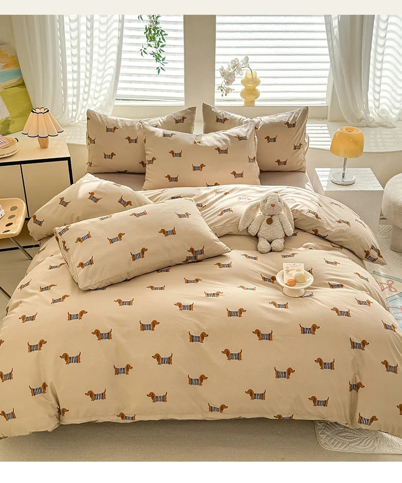 A beige duvet set featuring a cute dog print pattern, complete with pillows and a stuffed animal.