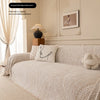 A light beige herringbone chenille sofa cover draped over a sofa in a bright, elegant living room setting.