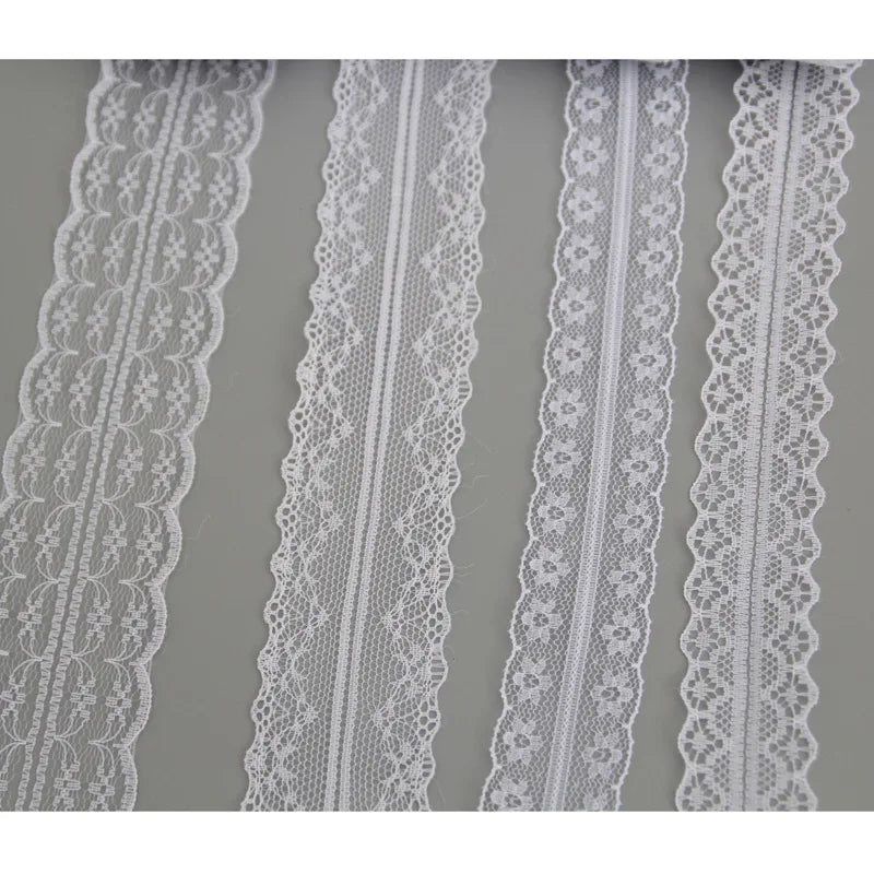 A close-up view of white floral lace ribbon trim in various patterns and widths for sewing and crafts.