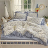 A light blue princess style ruffle bedding set with white floral patterns on a wooden bed frame.