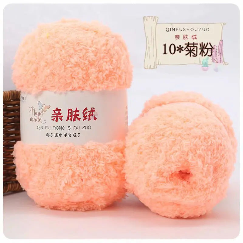 A package of soft coral pink velvet yarn is shown next to a finished ball of the same yarn for crafting.