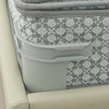 A close-up of a gray bed sheet corner tightener clip with a white patterned fabric, set against a light-colored frame.