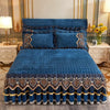 A deep blue velvet bed skirt with gold embroidery and ruffles is displayed on a bed.