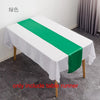 A white tablecloth with a green satin table runner is displayed on a table in a room.