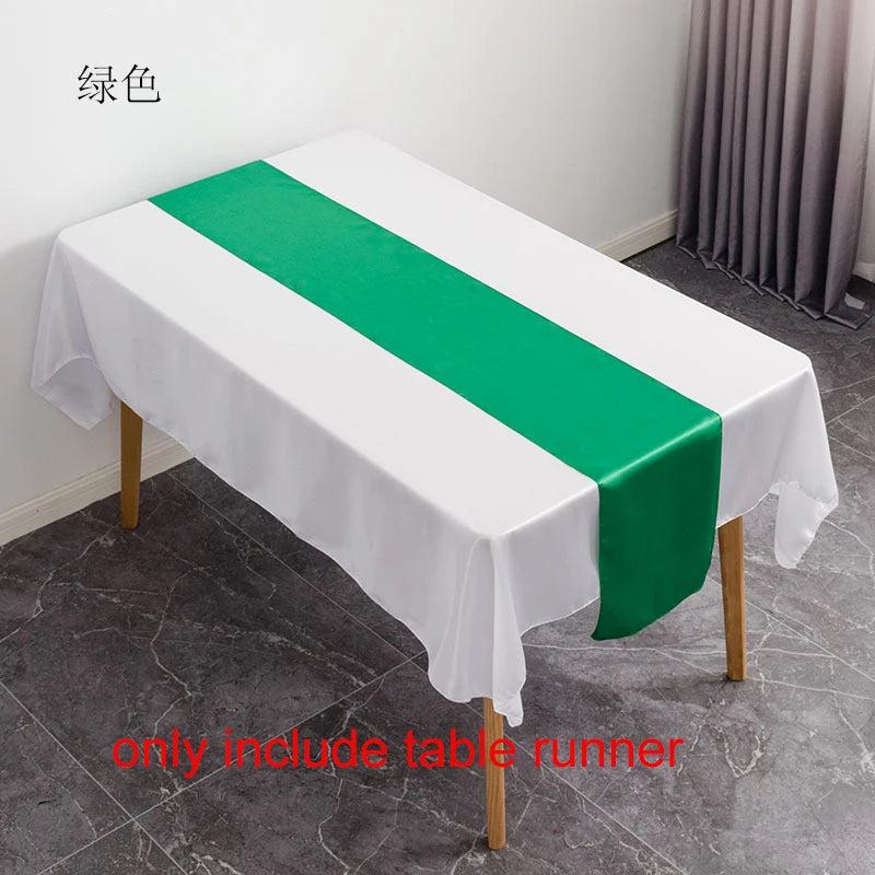 A white tablecloth with a green satin table runner is displayed on a table in a room.