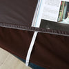 A dark brown waterproof stretch dining bench cover with a white tie closure is shown on a wooden surface.