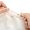A hand is using a stainless steel T-pin to mark fabric for knitting blocking or sewing.