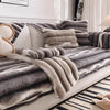 A plush sofa cover in gray stripes with a light beige throw draped over the fabric.