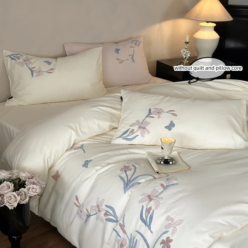 White duvet cover set featuring embroidered orchid patterns and lace trim on a bed.