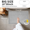 A gray waffle design non-slip bathroom mat is shown placed on a tiled floor, with a foot resting on it.