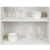 White ceramic bowls and clear glassware displayed on a white shelf inside a cabinet.