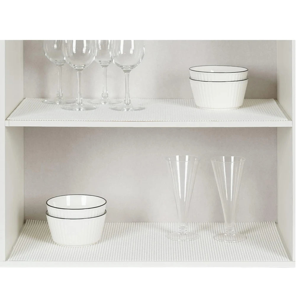 White ceramic bowls and clear glassware displayed on a white shelf inside a cabinet.