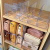 A clear plastic storage organizer with four sections is displayed on a wooden shelf.