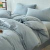 A light blue cotton yarn-dyed duvet cover with matching pillows on a bed.