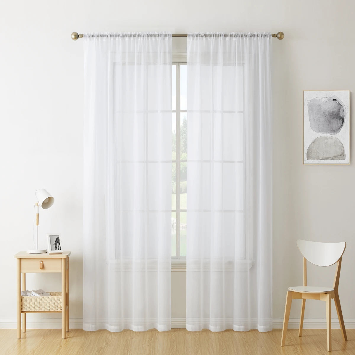 A pair of sheer white voile curtains hanging in a window frame.