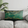 A dark teal pillow cover featuring a geometric pattern of gold lines and speckles.