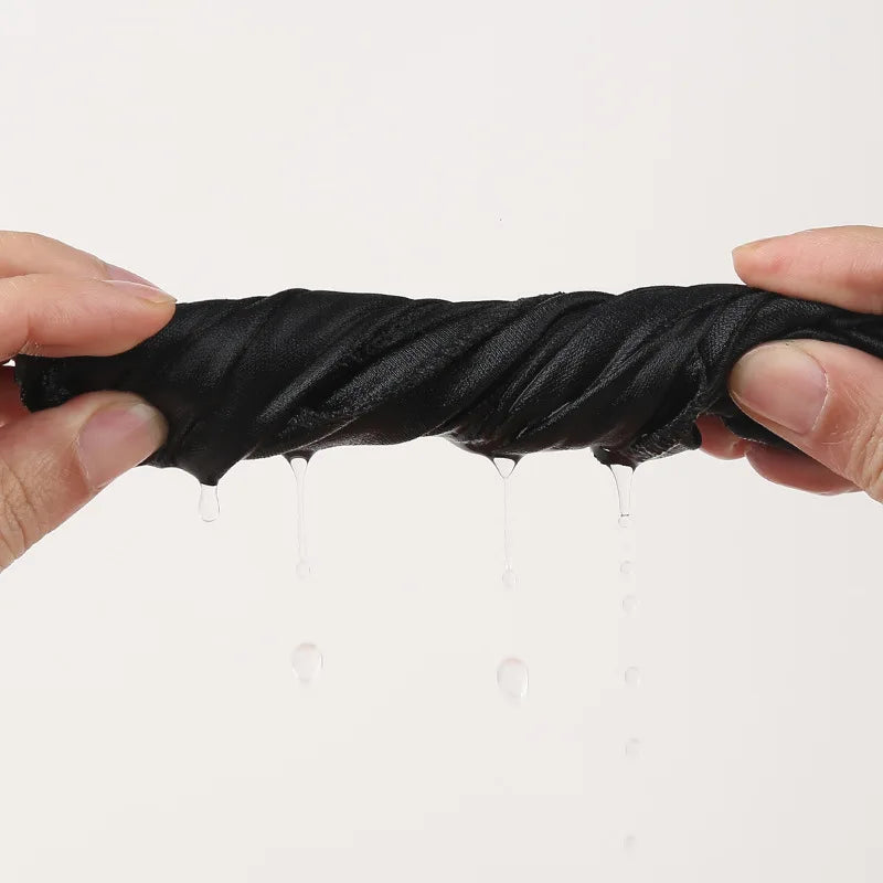 A hand is holding a black paisley print headwrap, showing dripping moisture.