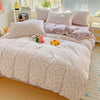 A light pink floral printed bedding set with matching pillows and a duvet on a bed.
