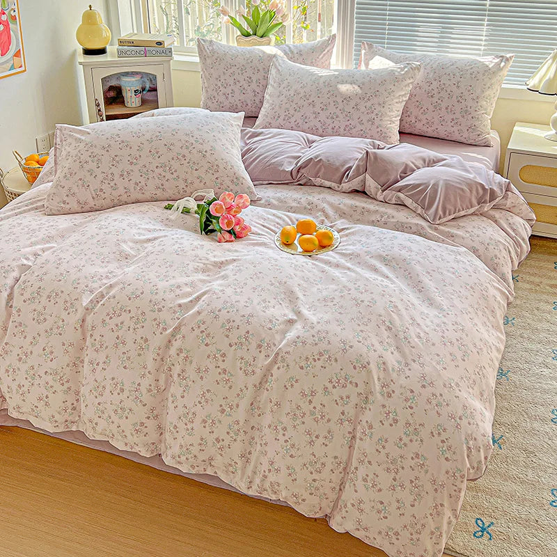 A light pink floral printed bedding set with matching pillows and a duvet on a bed.