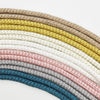 A collection of beige, white, and gray braided ropes or cords arranged in an arc.