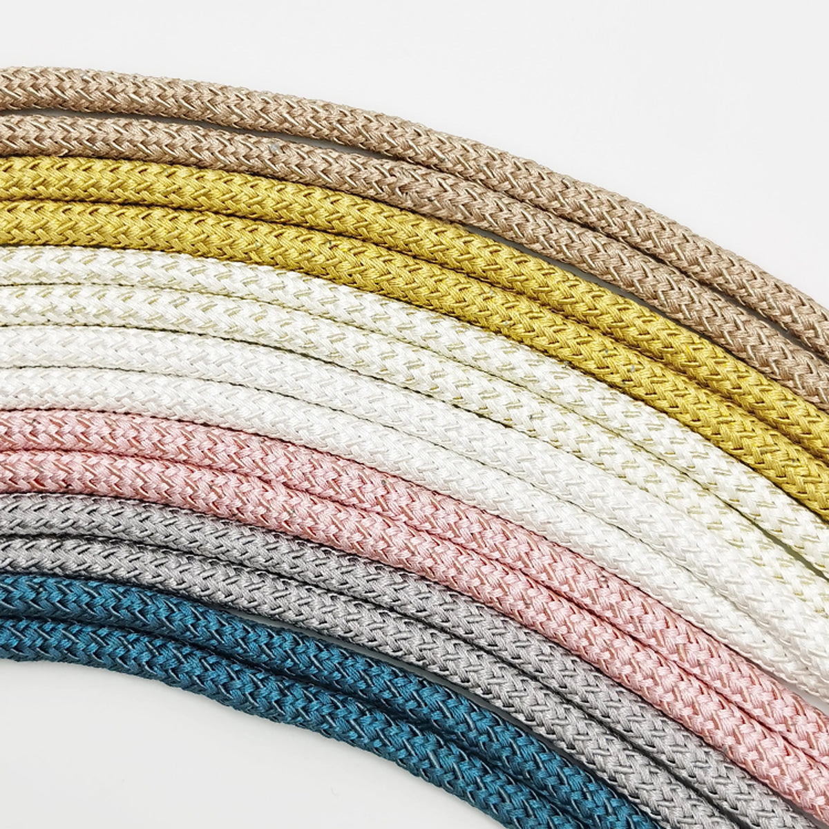 A collection of beige, white, and gray braided ropes or cords arranged in an arc.